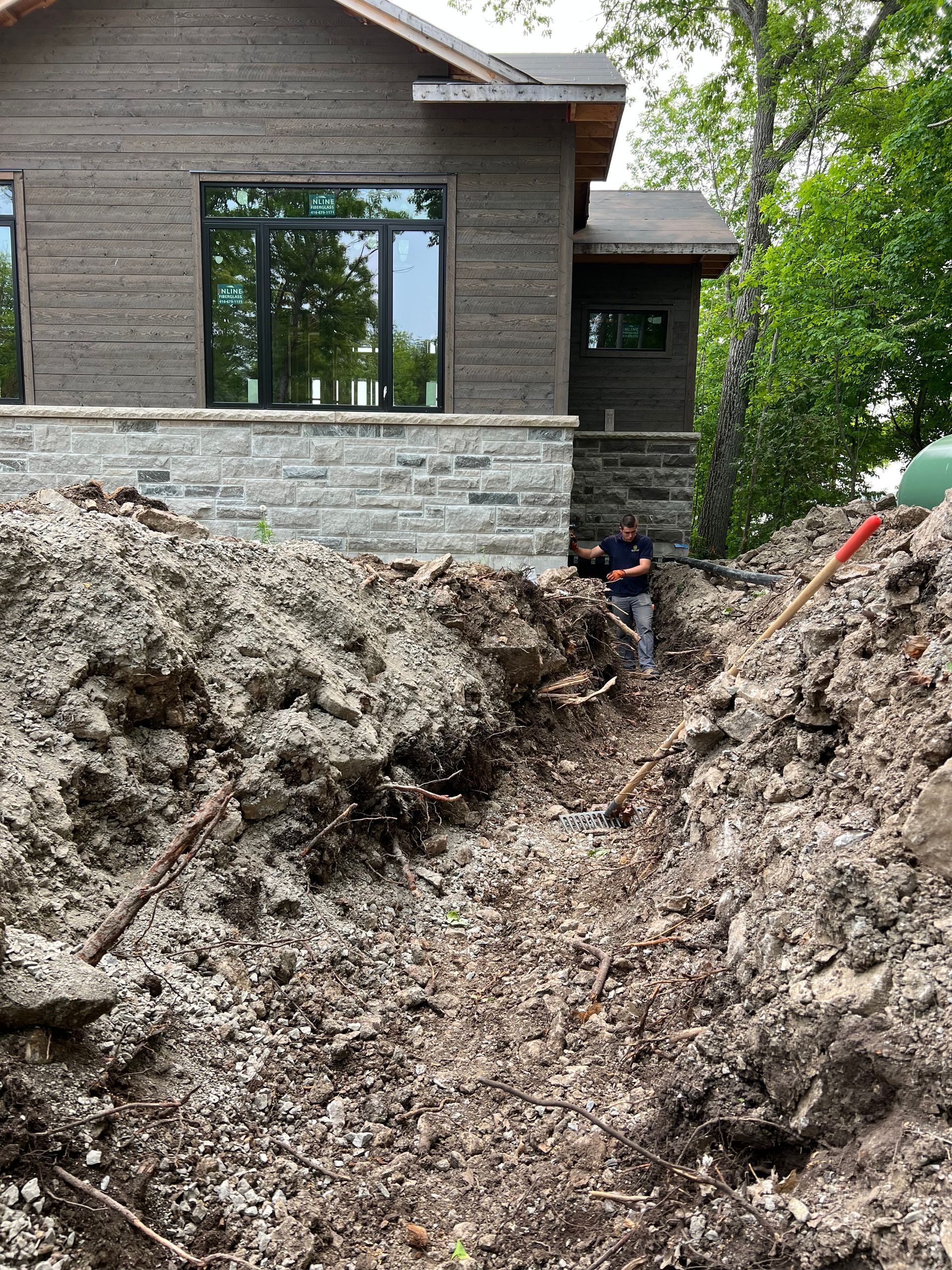 A man is sitting on a pile of dirt in front of a house.