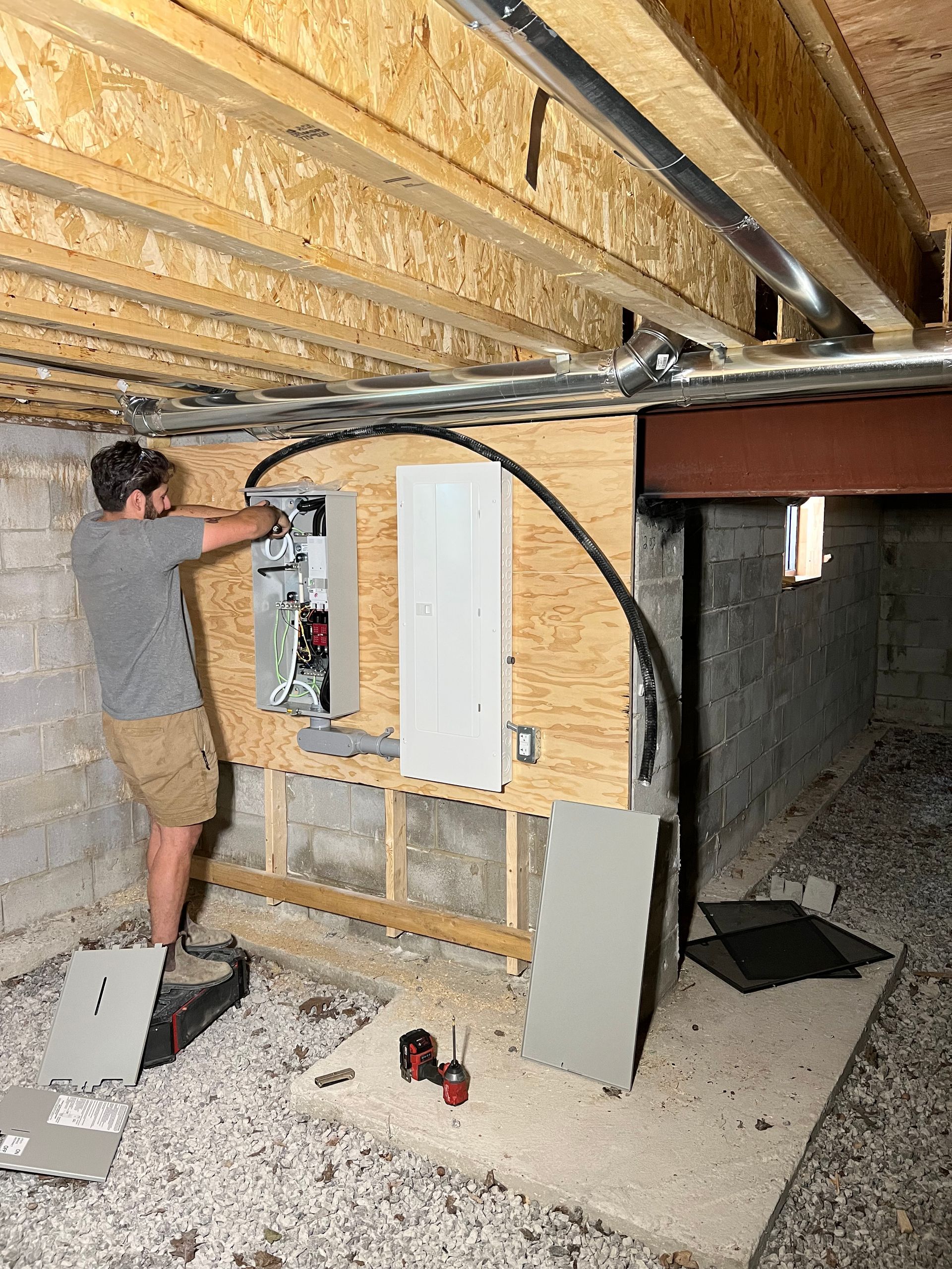 A man is working on an electrical box in a basement.