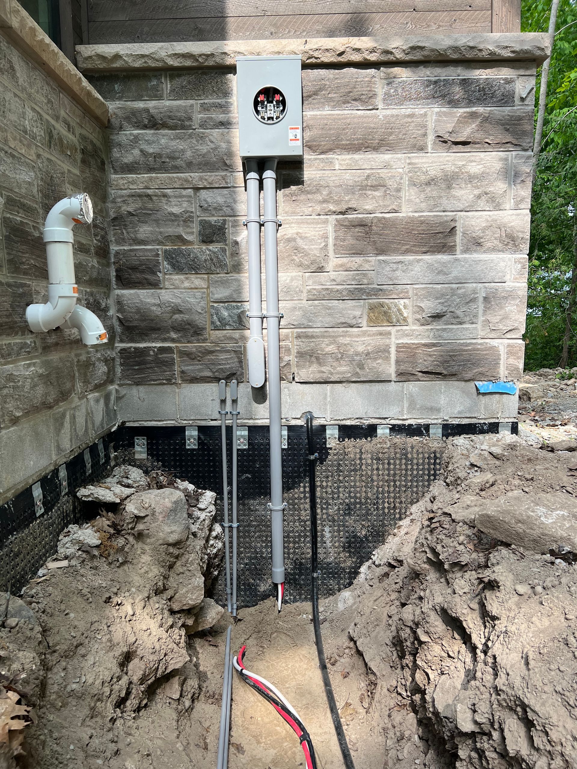 An electrical box is being installed on the side of a brick building.
