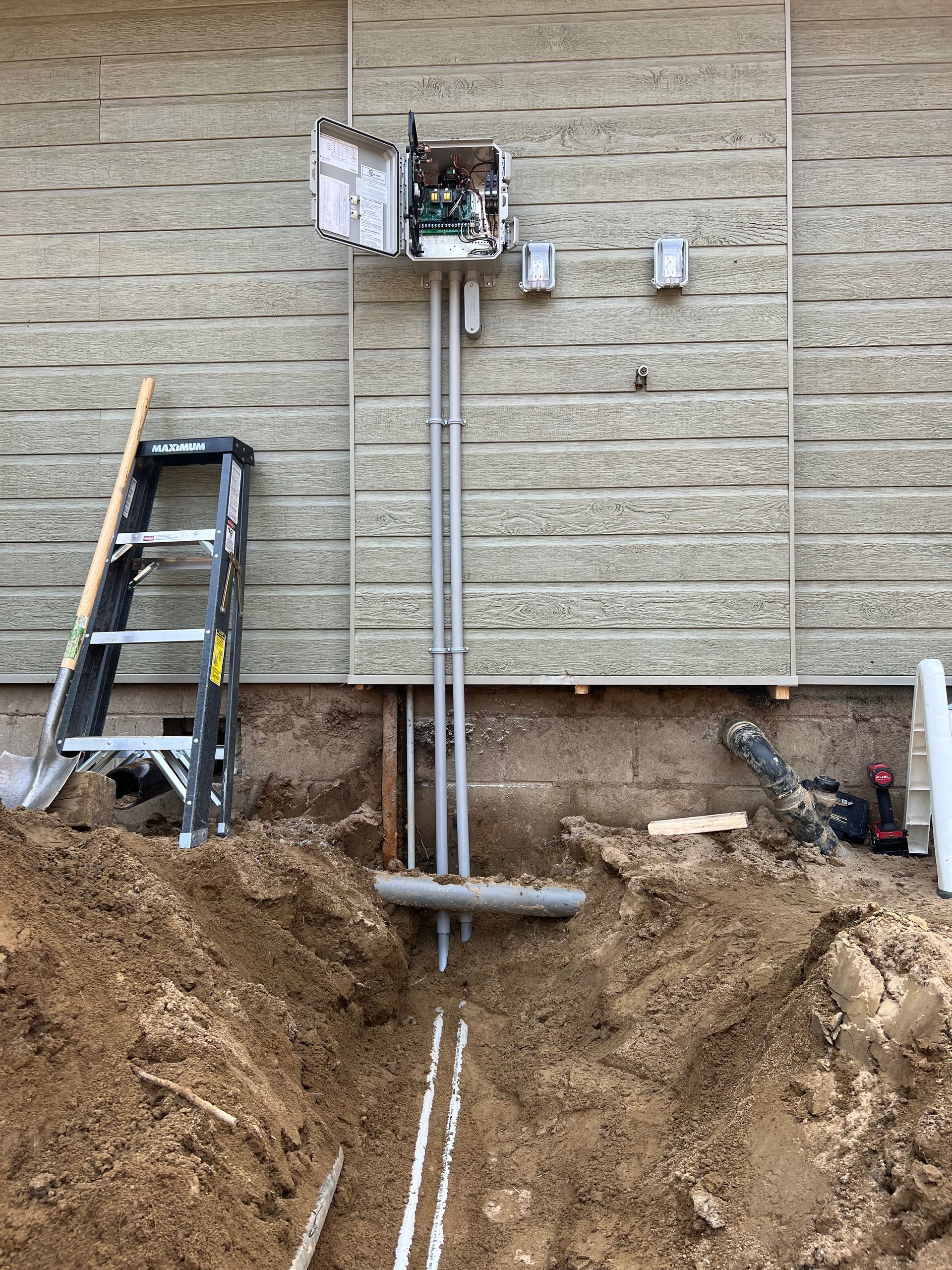 A ladder is sitting next to a box on the side of a building.