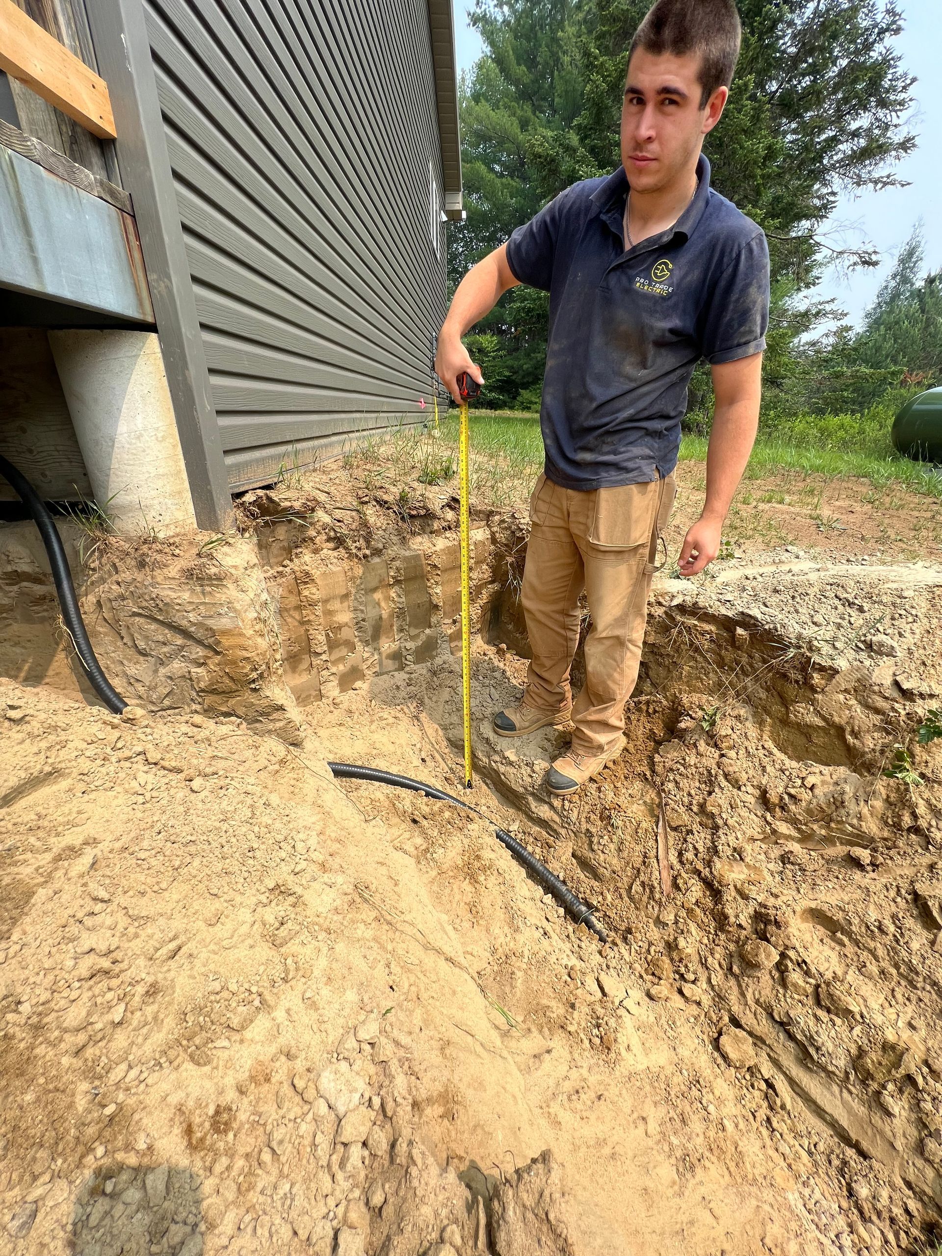 A man is measuring a hole in the ground with a tape measure.