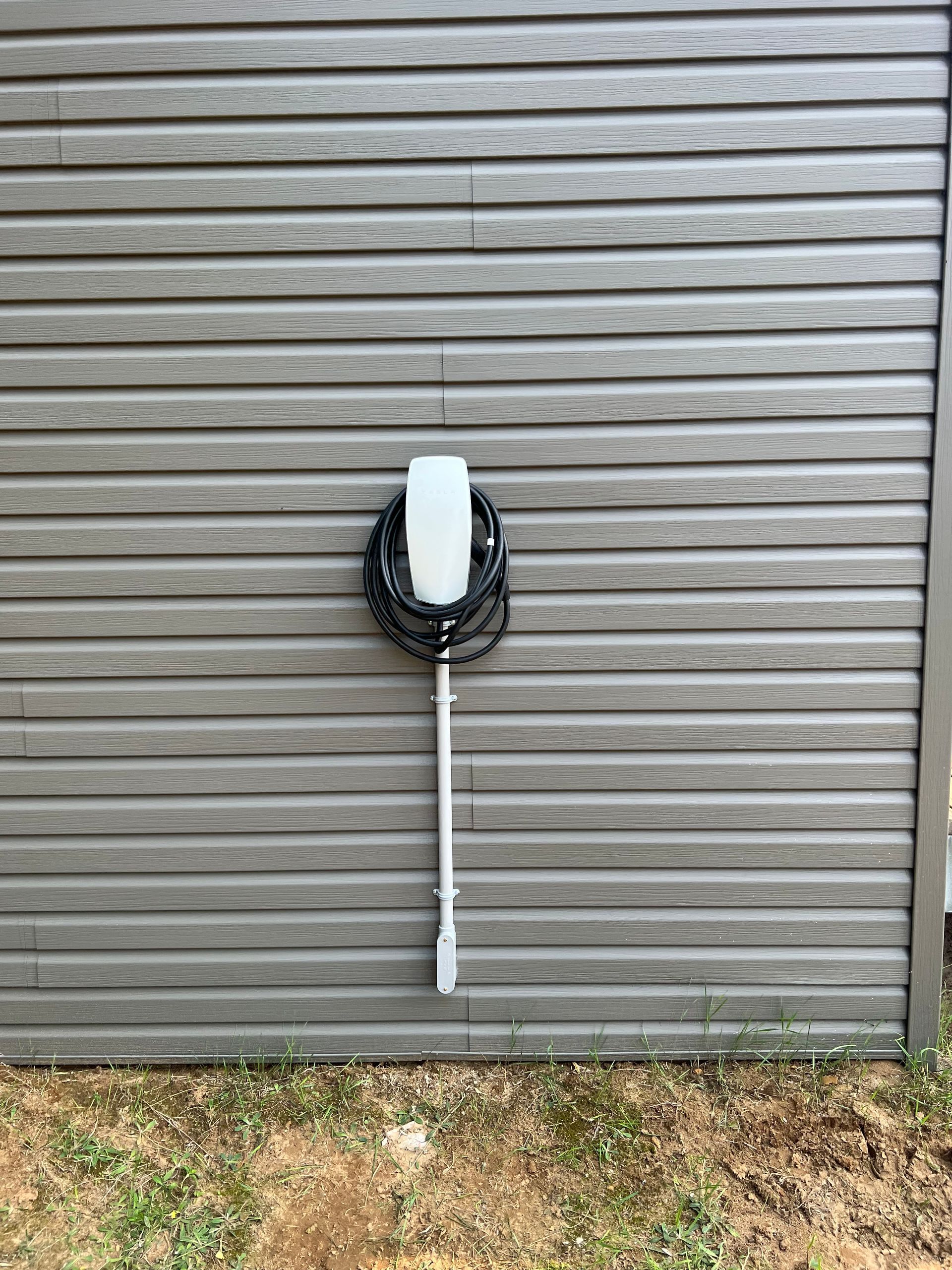 A tesla charging station is attached to the side of a building.