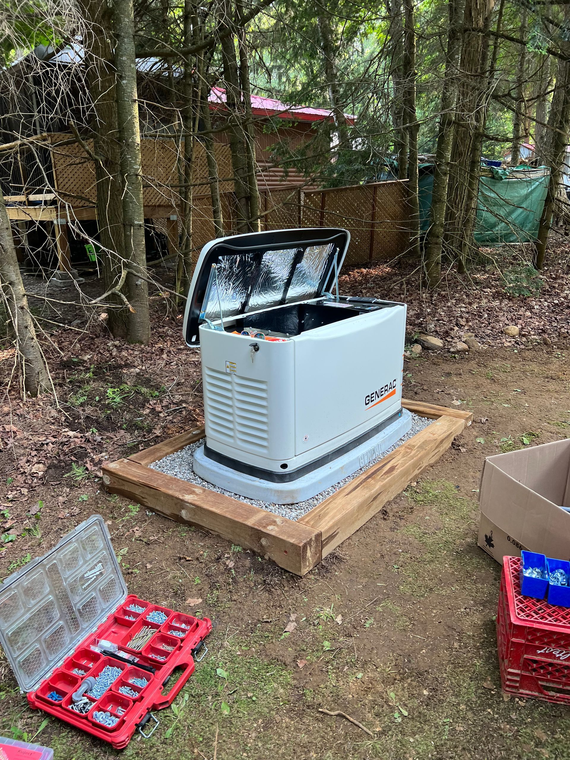 A generator is sitting on top of a wooden platform in the woods.