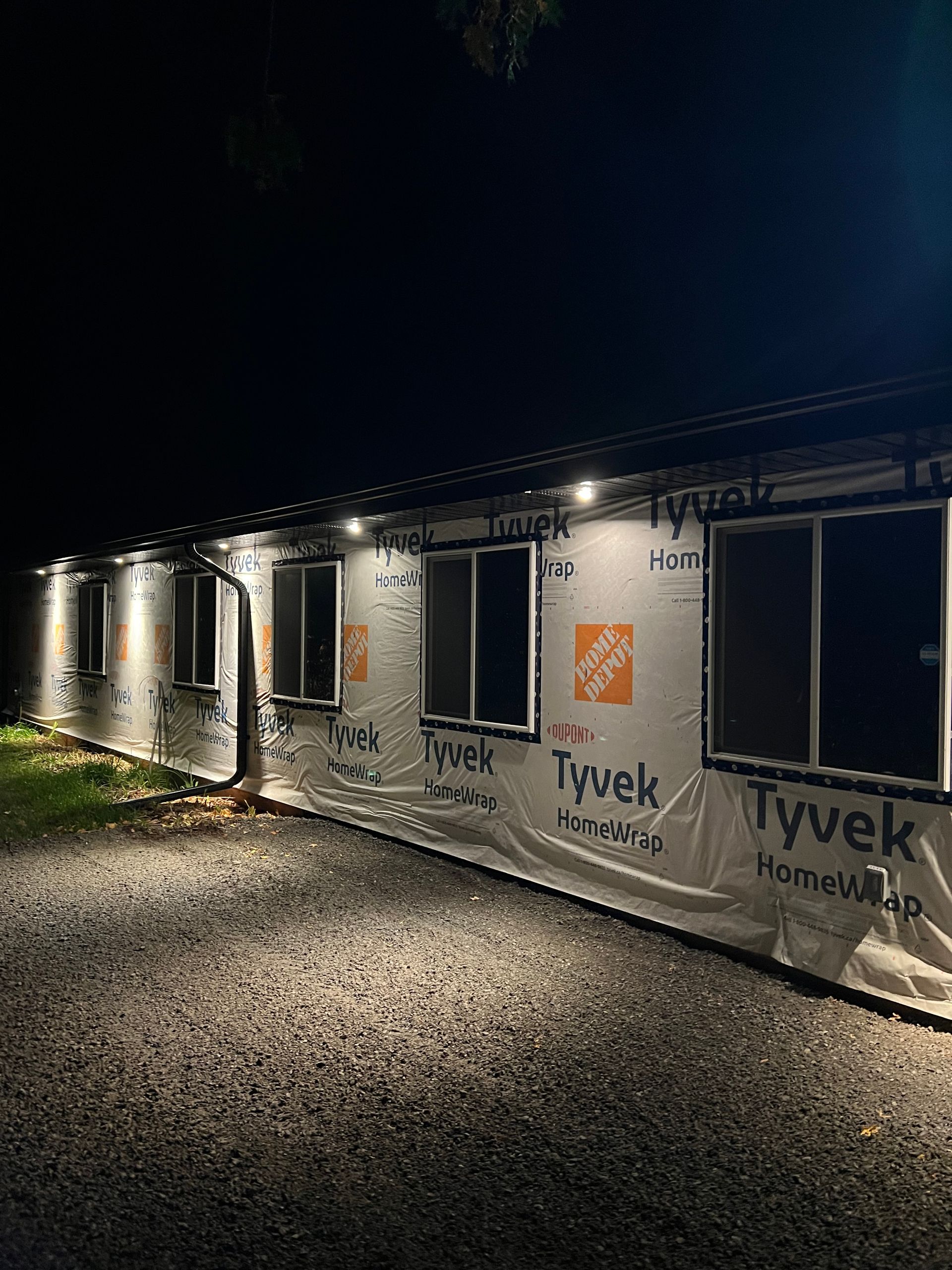 A house with a lot of windows is being built at night.