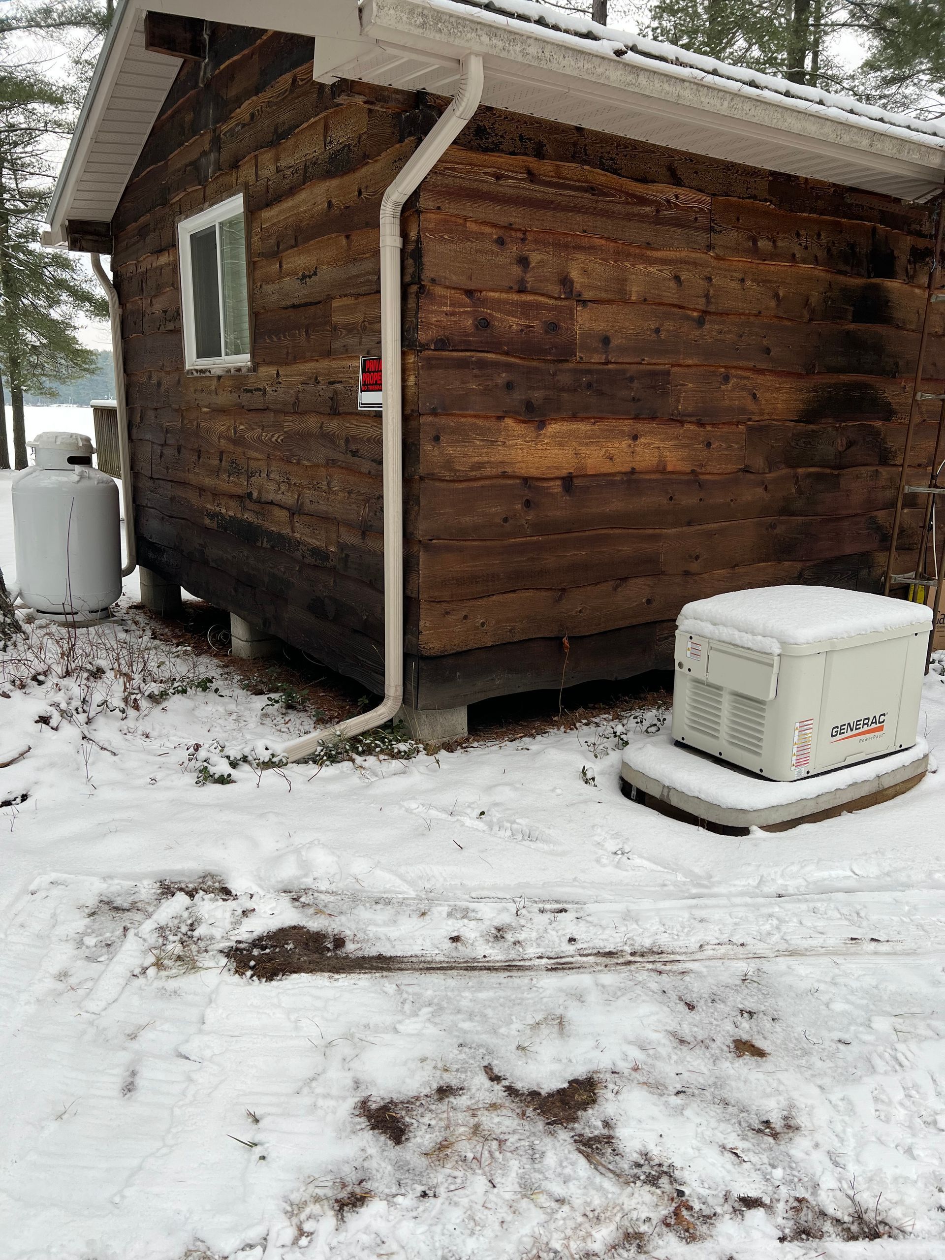 A log cabin in the snow with a cooler in front of it
