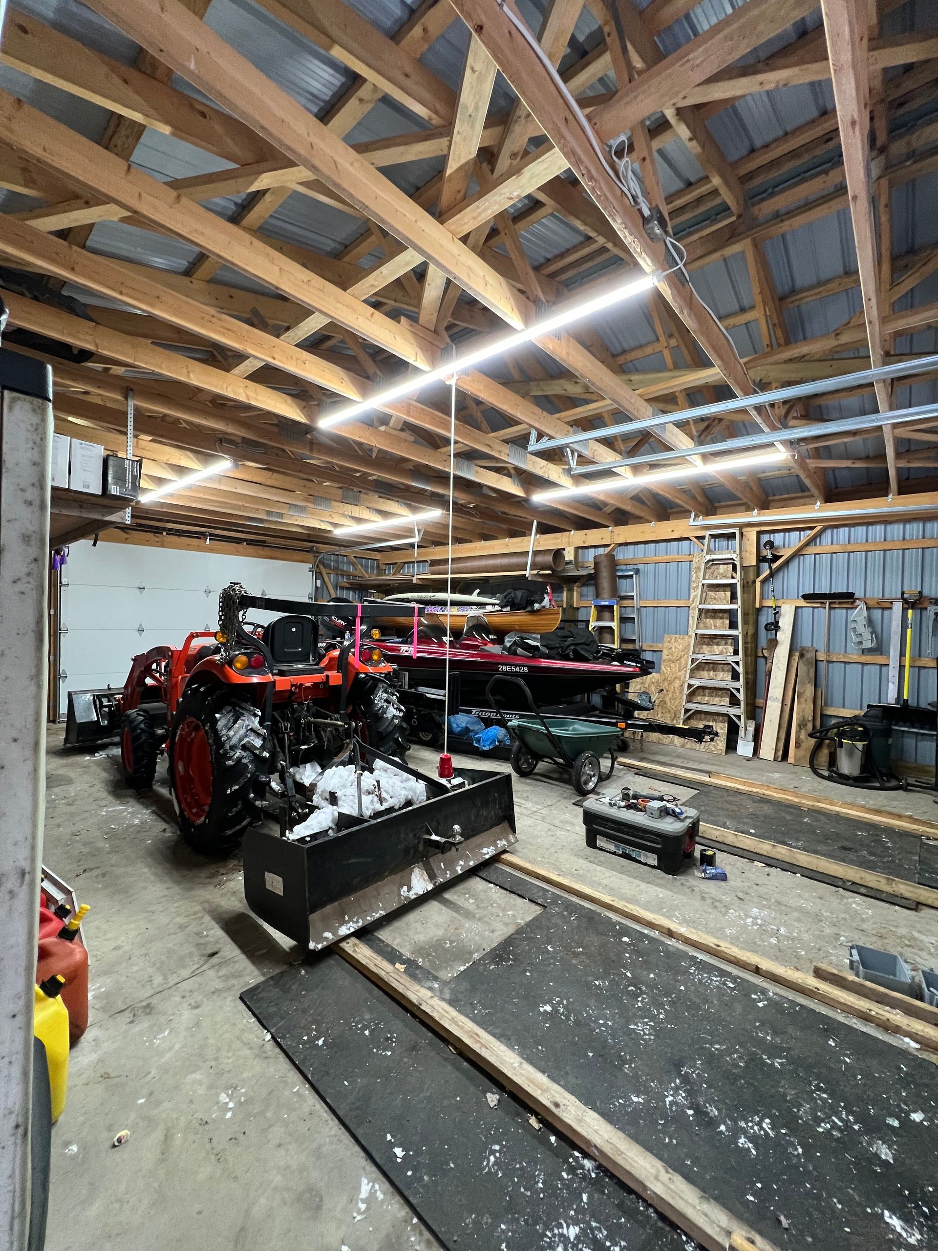 A garage filled with lots of vehicles and a snow plow.