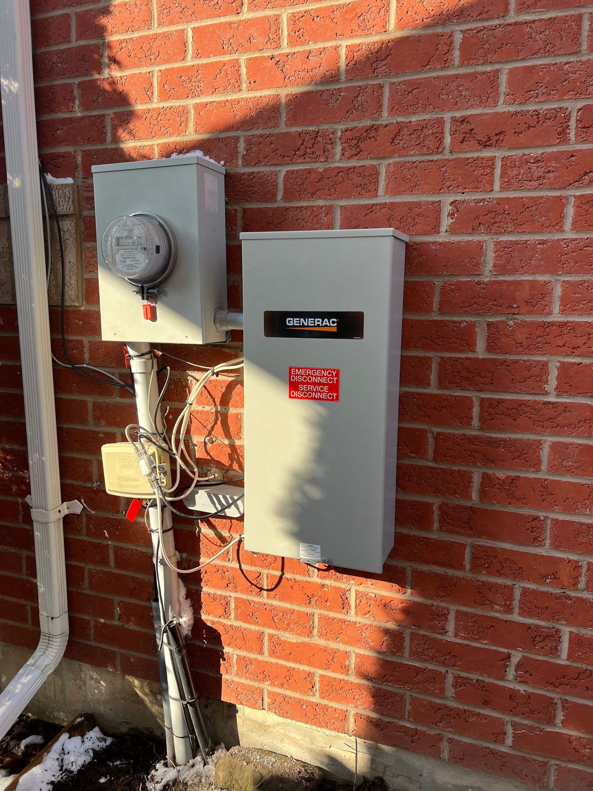 A brick wall with a white box mounted to it.