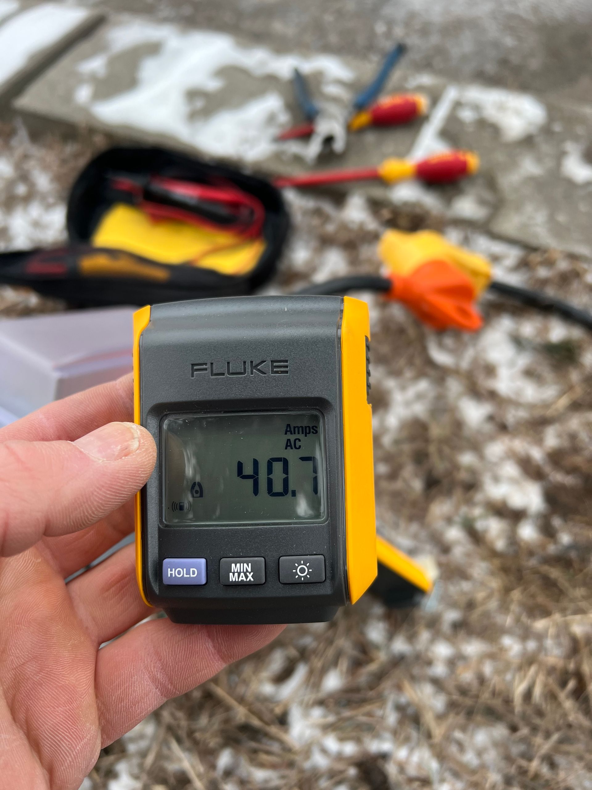 A person is holding a fluke meter in their hand.