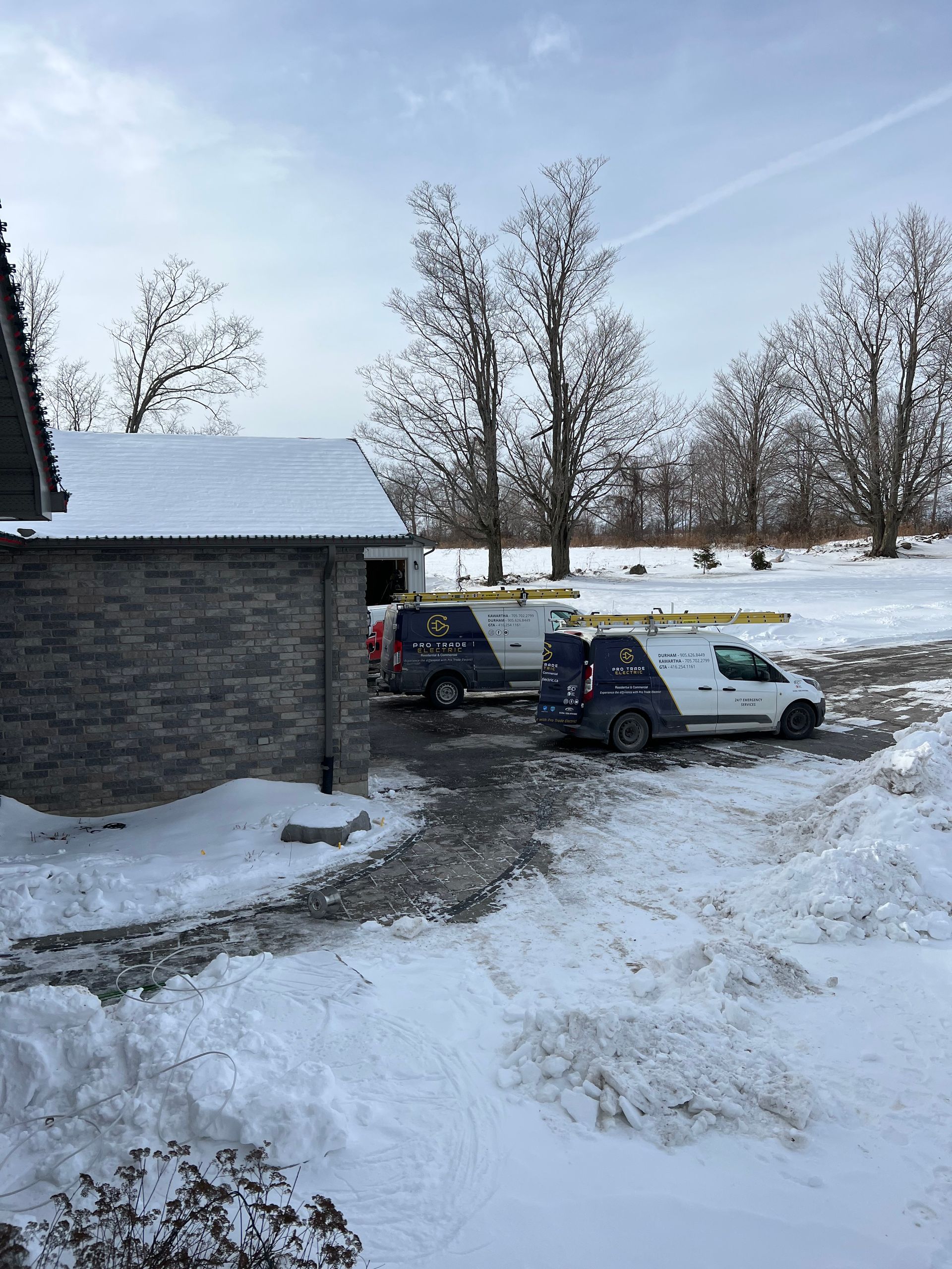 Two vans are parked in the snow in front of a house.