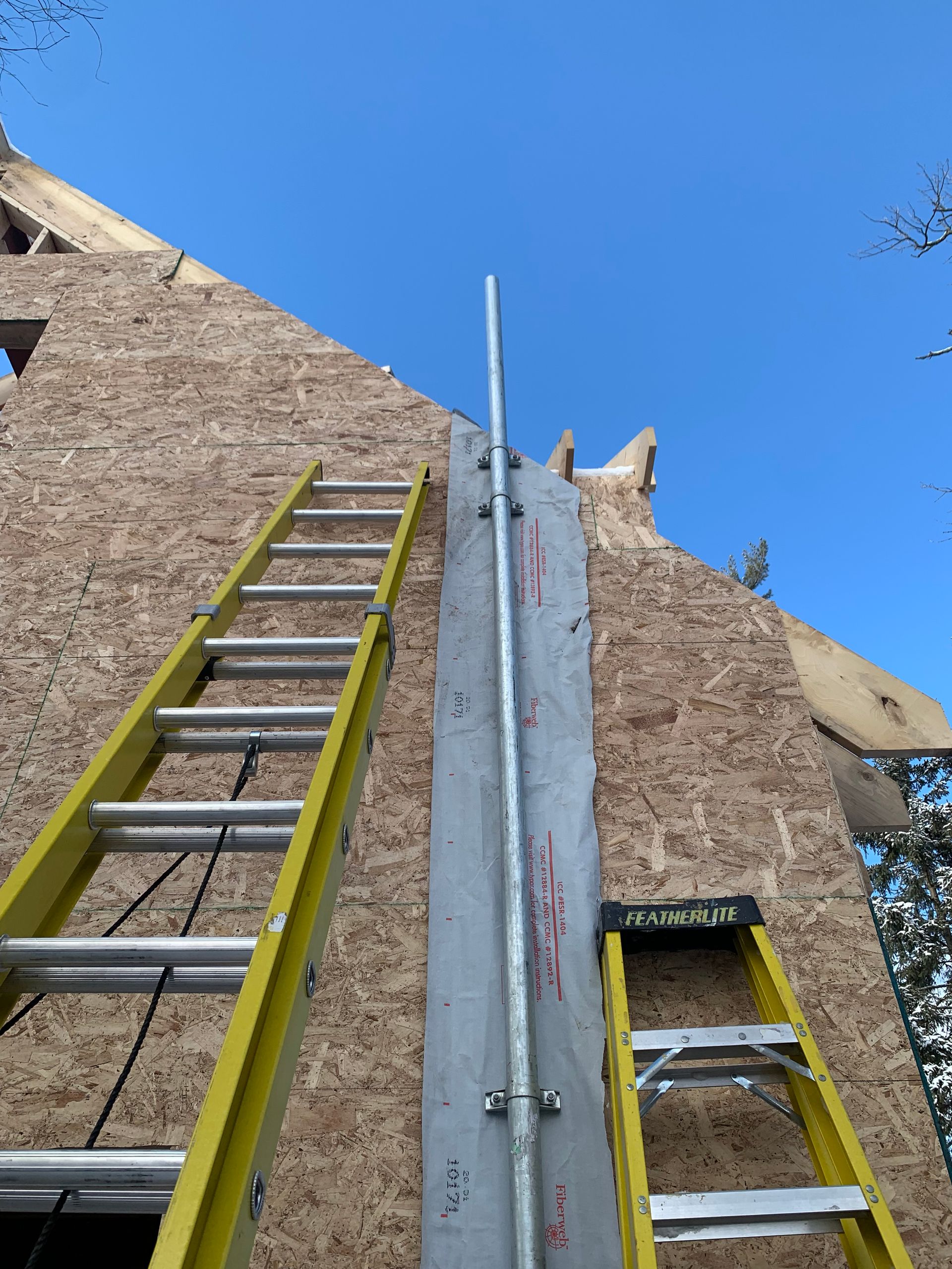 Two ladders are sitting on top of a wooden wall.