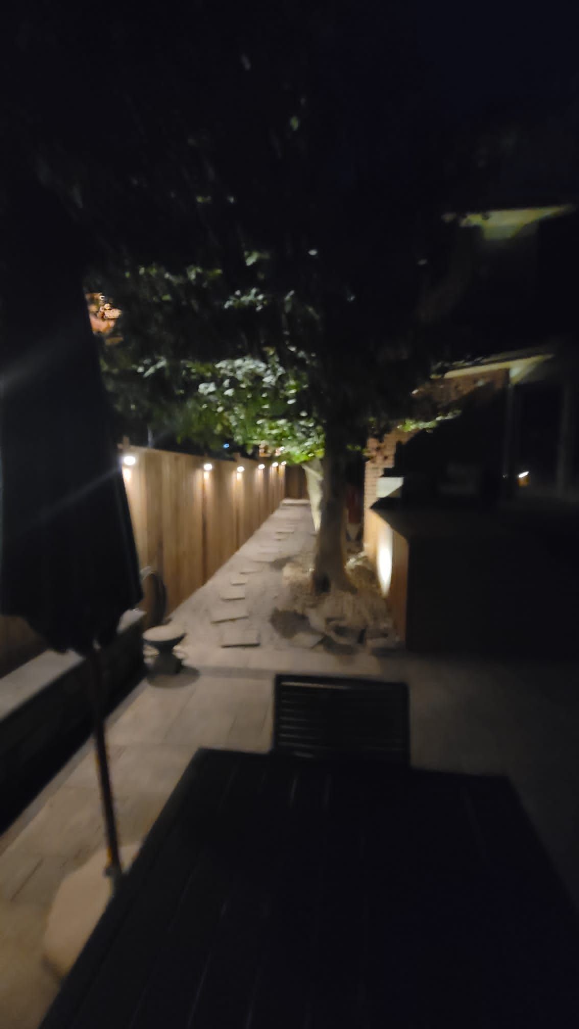 A patio at night with a table and chairs and umbrellas.