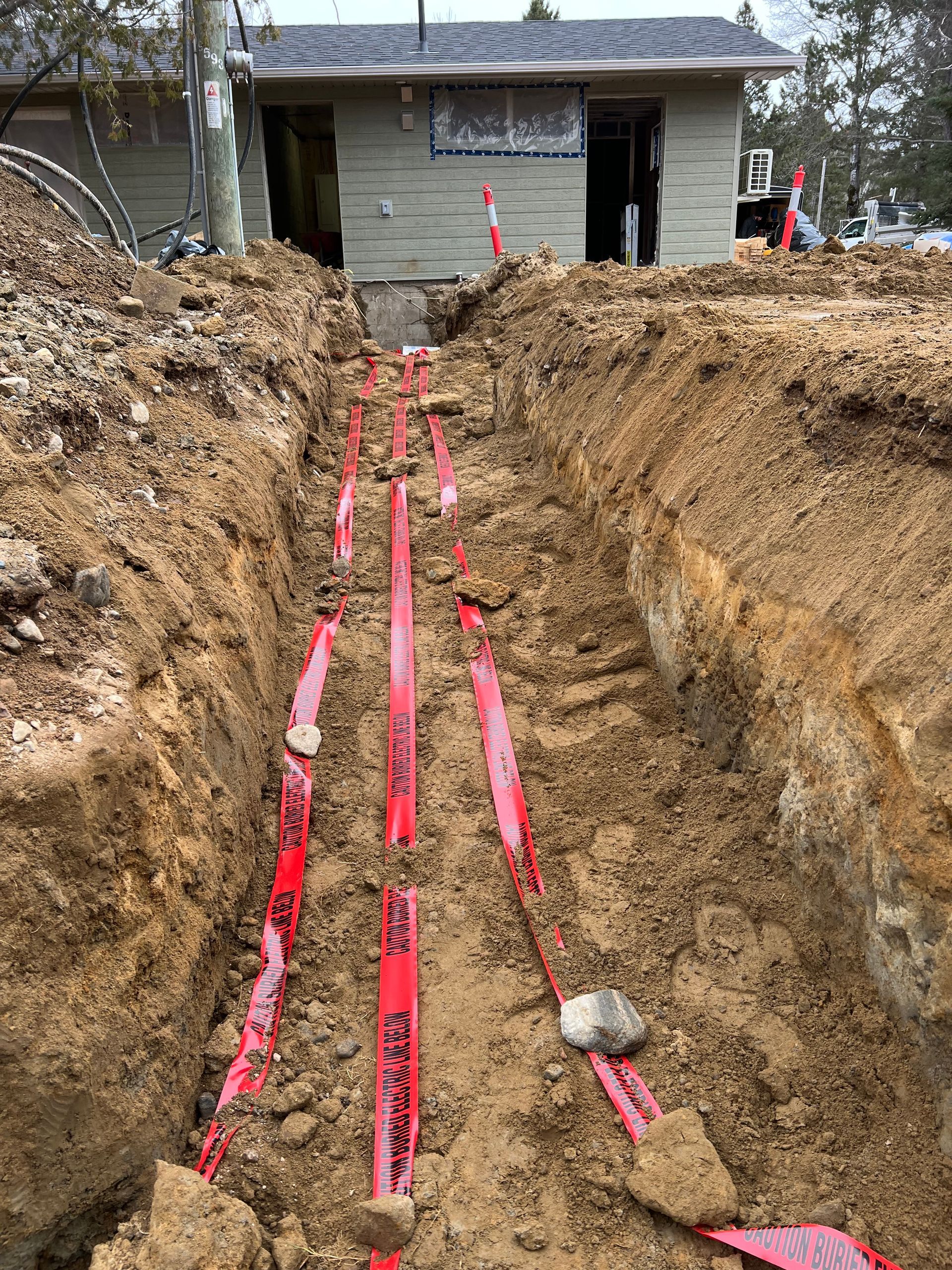 A house is being built and a trench is being dug in front of it.