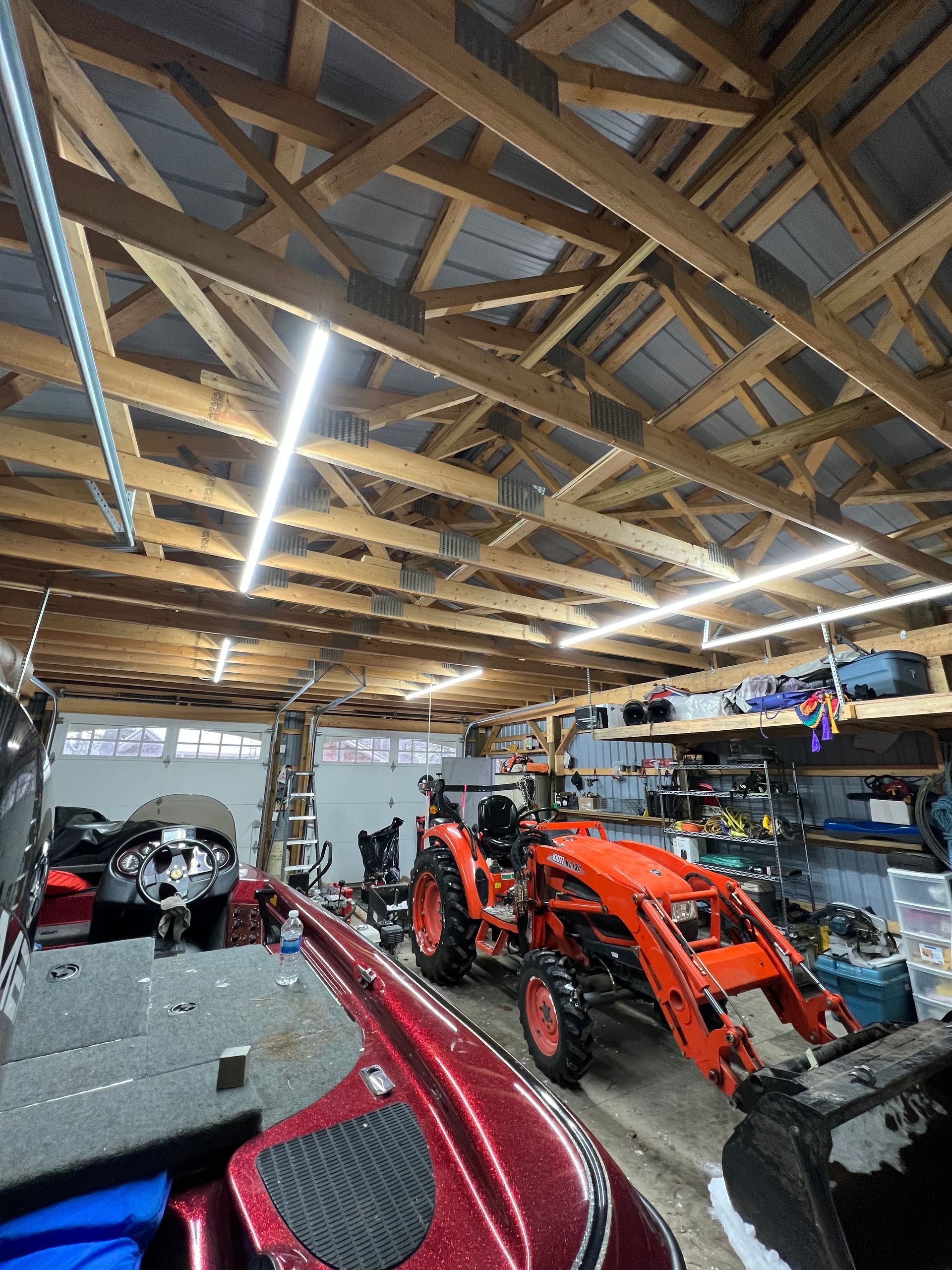 A tractor is parked in a garage next to a boat.