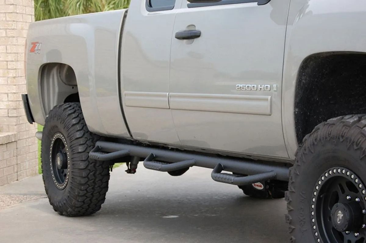 Lifted gray pickup truck with off-road tires parked beside a brick wall