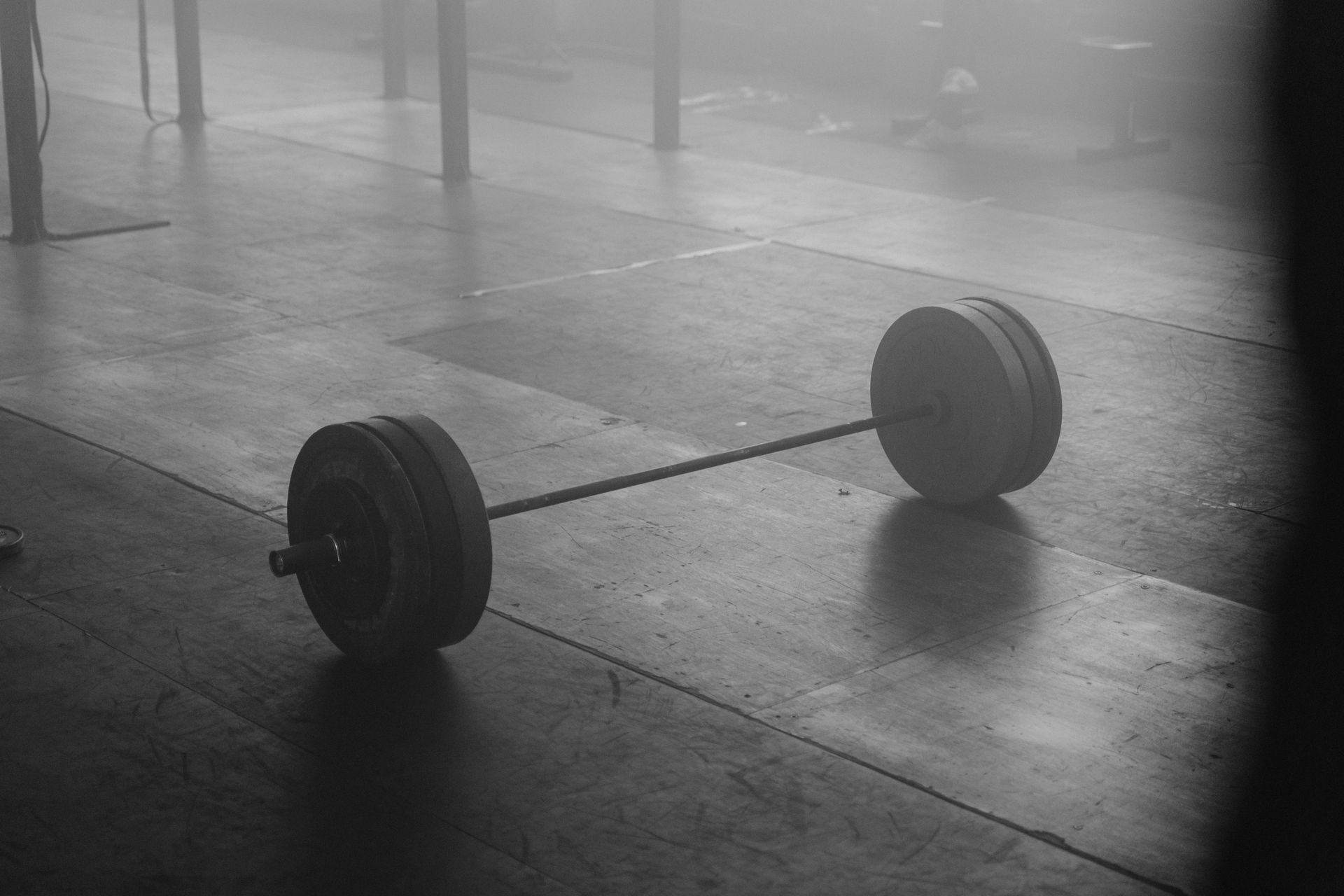 A loaded barbell resting on the floor of a quiet gym
