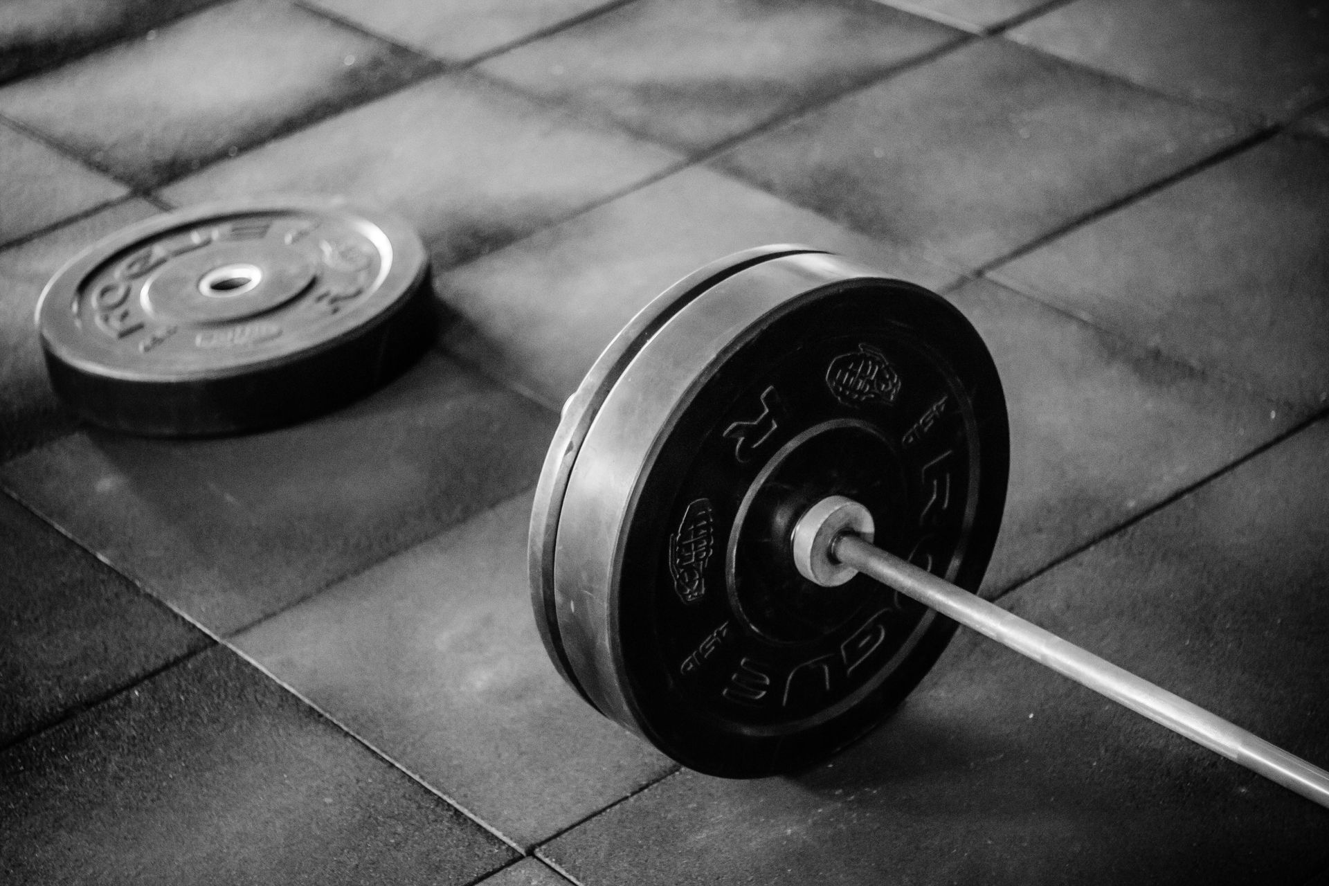 Black and white barbell with weight plates on a textured gym floor.