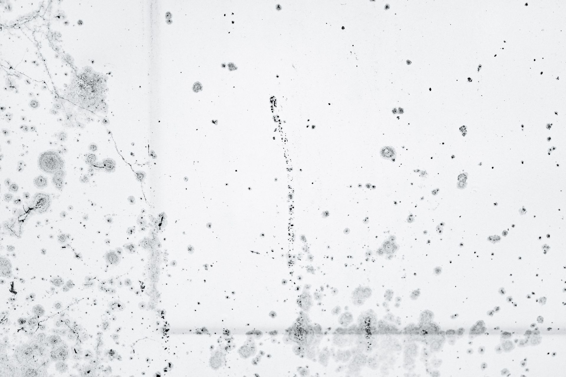 Person in protective suit cleaning a dirty floor with a spray bottle near a wall and radiator