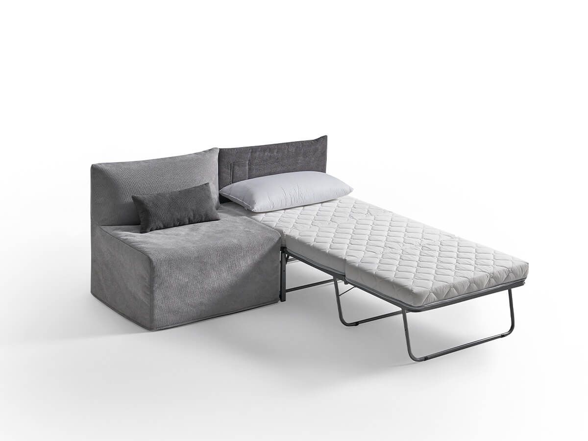 Divano componibile grigio con letto estraibile, materasso bianco esteso, due cuscini.