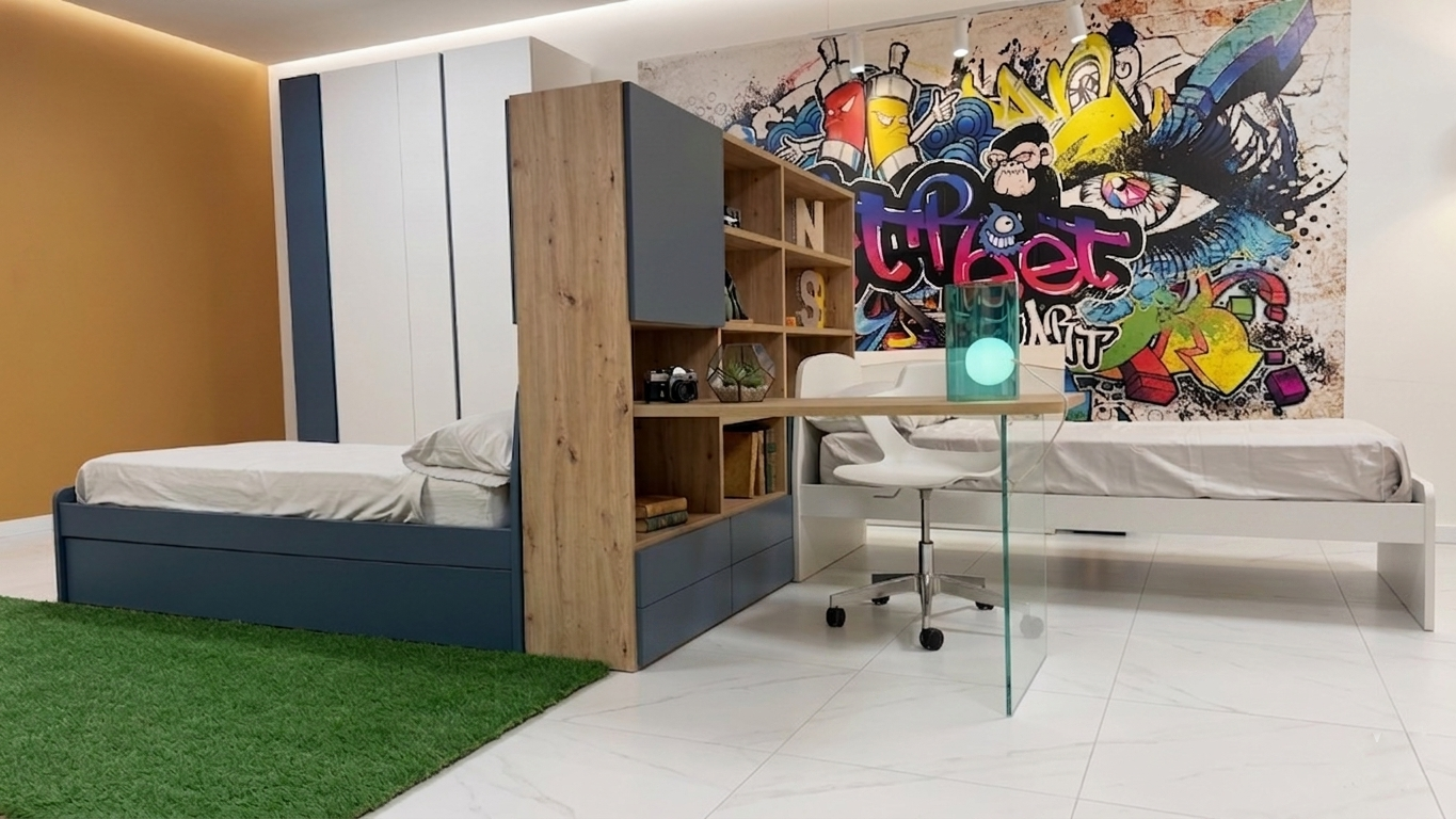 Cameretta per bambini con due letti, scrivania e un murale con graffiti.