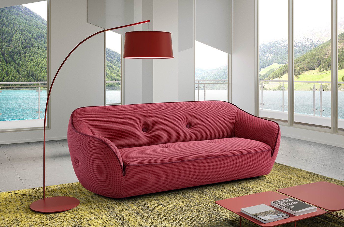 Divano rosso e lampada da terra in un soggiorno luminoso con vista sul lago.