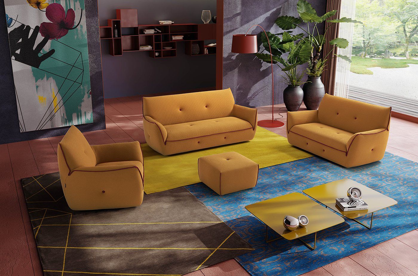 Soggiorno con divano color senape, poltrona e pouf su un tappeto a fantasia; tavolini da caffè.