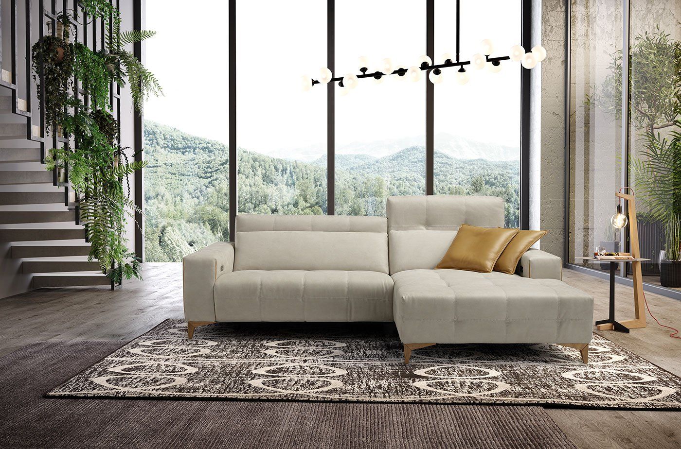 Divano componibile beige in una stanza luminosa con vista sulle montagne e piante.