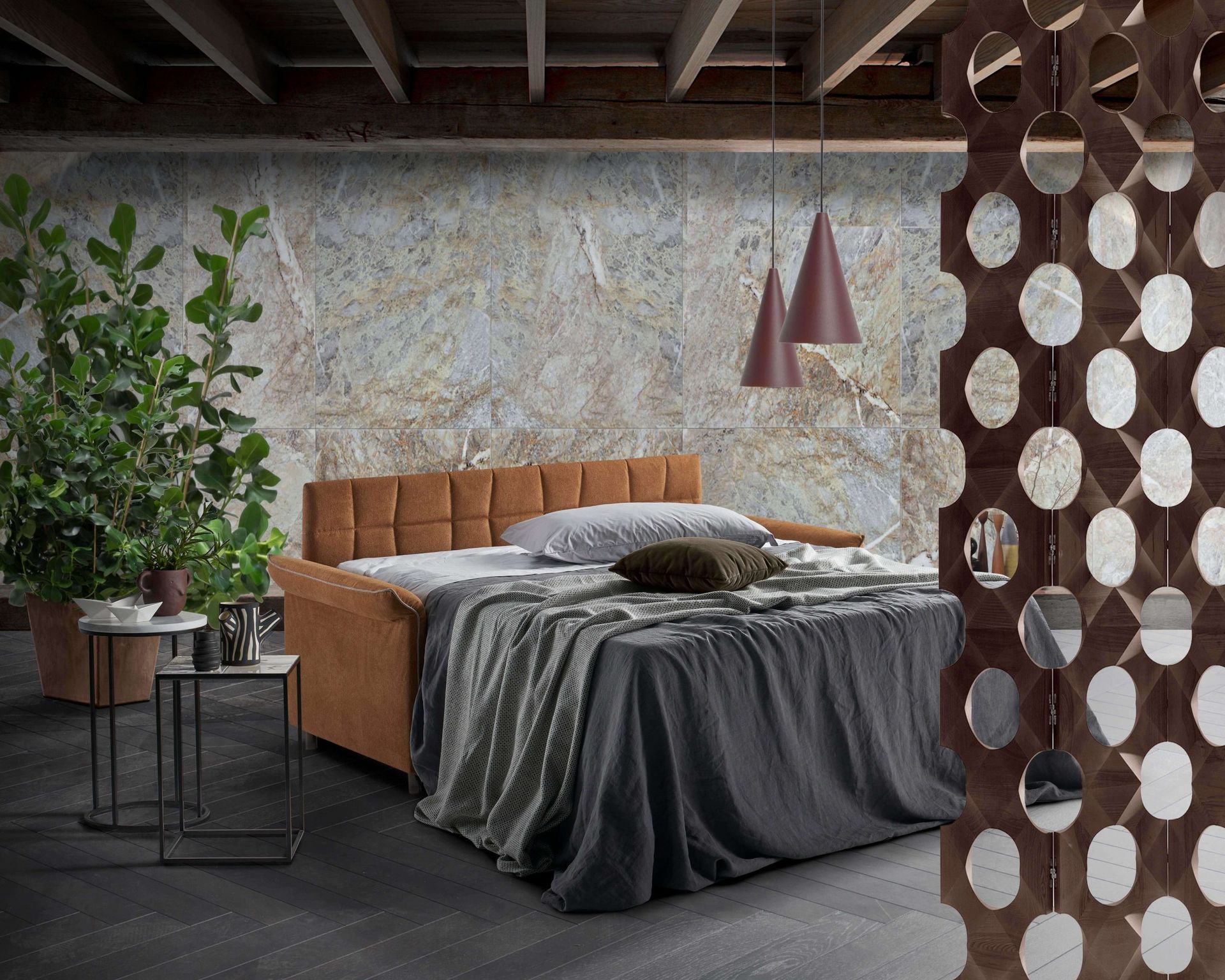 Camera da letto con divano letto marrone, biancheria grigia, paravento decorativo e grande pianta.