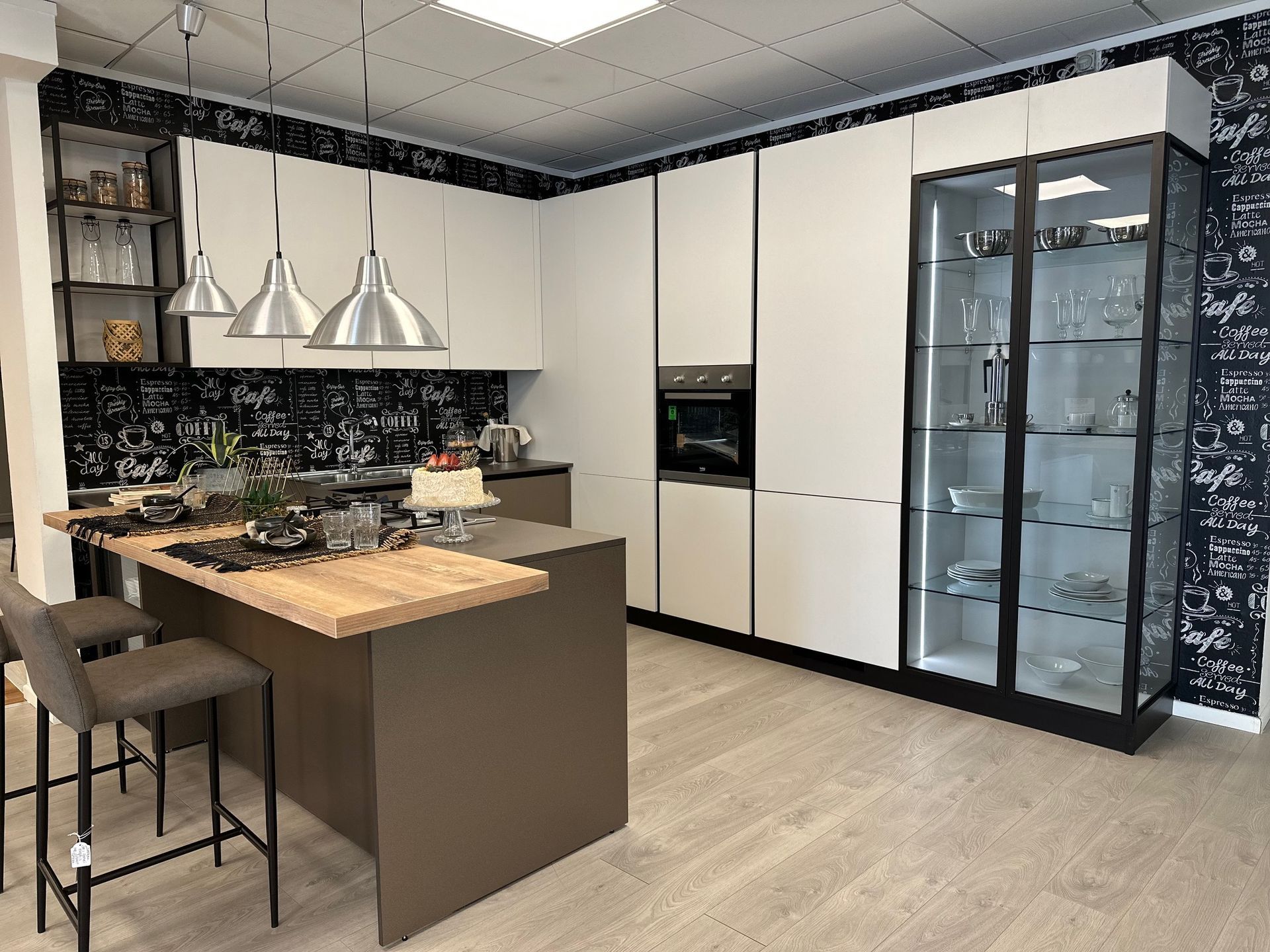 Cucina moderna con mobili bianchi, isola scura, elettrodomestici in acciaio inossidabile e vetrina.