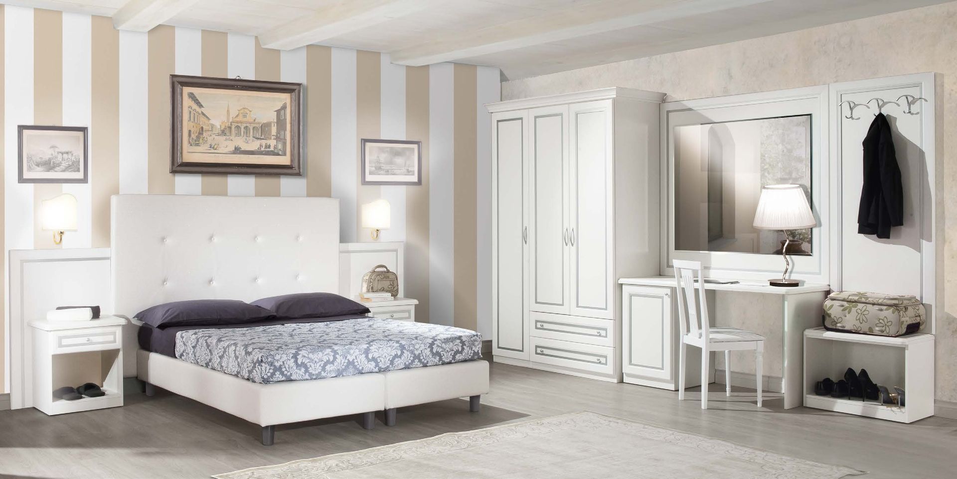 Camera da letto con mobili bianchi, pareti a strisce, letto con lenzuola scure e set da toeletta.