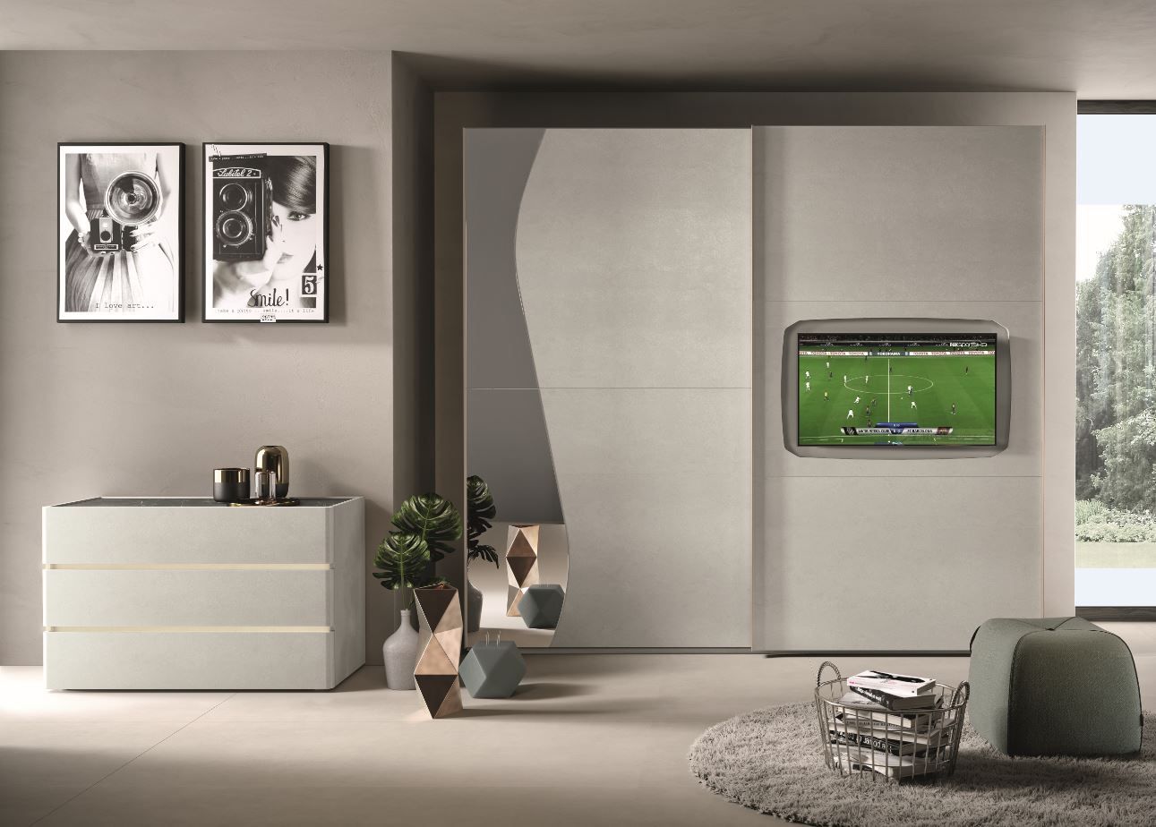 Camera da letto moderna con pareti grigio chiaro, cassettiera bianca, ante scorrevoli dell'armadio con un design astratto e TV montata a parete.