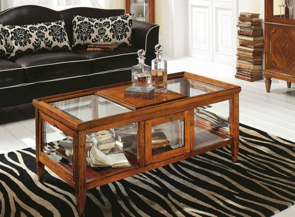 Soggiorno con tavolino da caffè in legno marrone, pannelli in vetro, libri, decanter per liquori e tappeto zebrato.