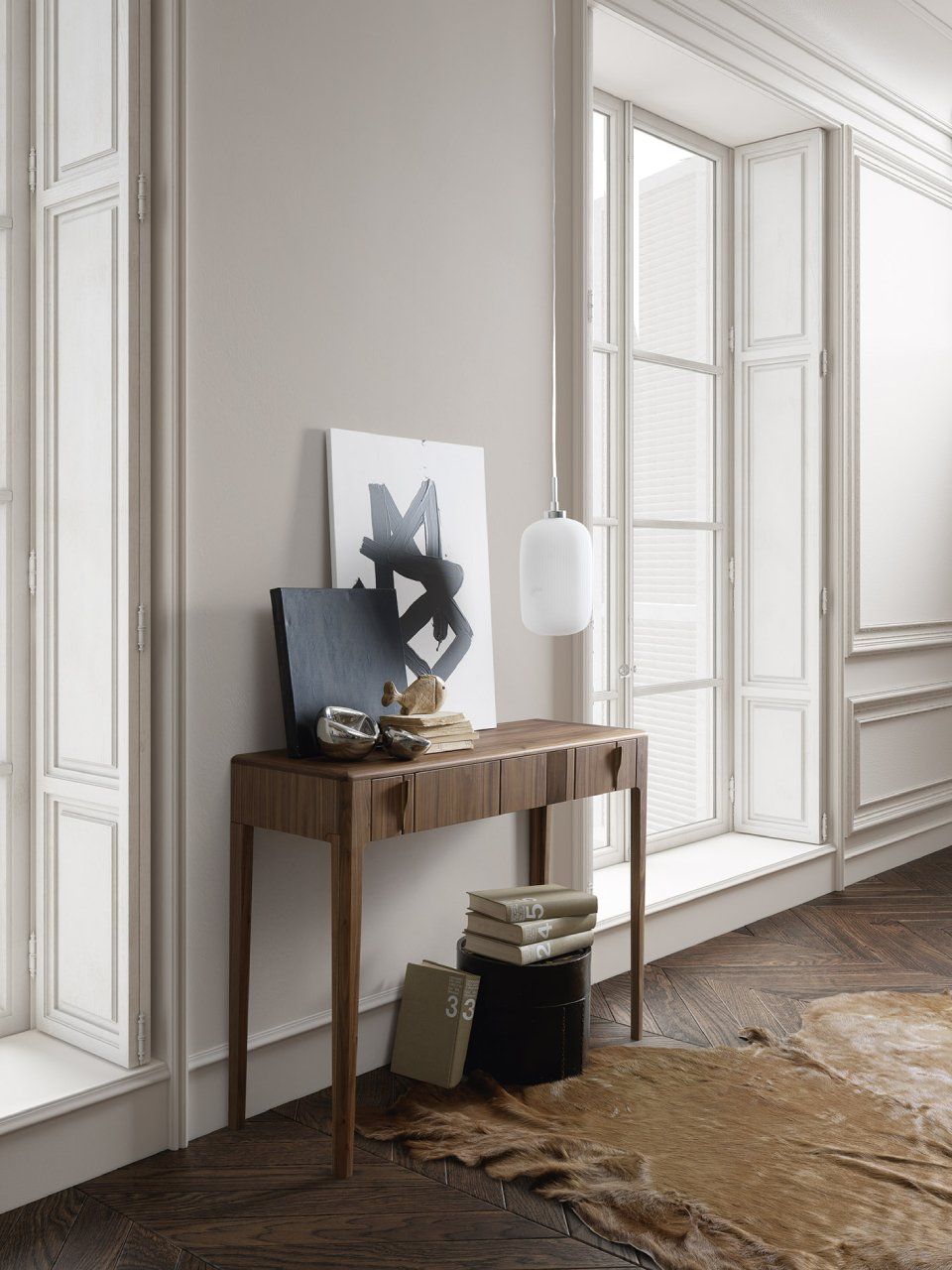 Consolle in legno con opere d'arte, finestra e tappeto in una stanza dai toni neutri.