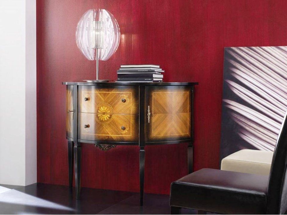 Mobile decorato con lampada su una parete rossa; libri, sedia e opere d'arte in vista.