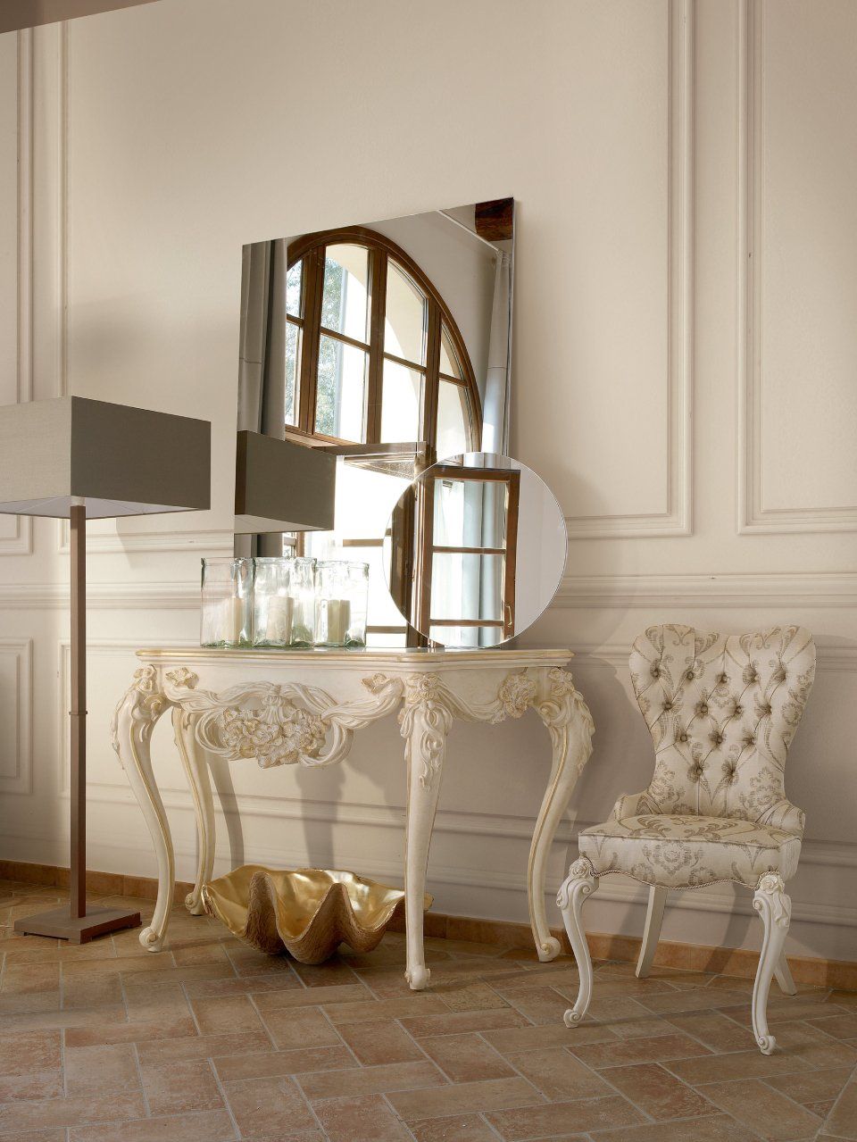 Elegante tavolo da toeletta bianco, sedia e specchio contro una parete, con una lampada da terra e oggetti decorativi.
