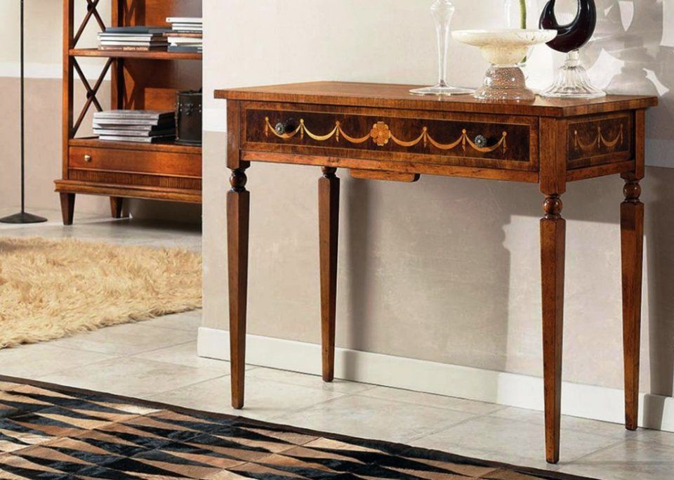 Un tavolo consolle in legno con un cassetto decorativo, posizionato in una stanza con un tappeto e una libreria.