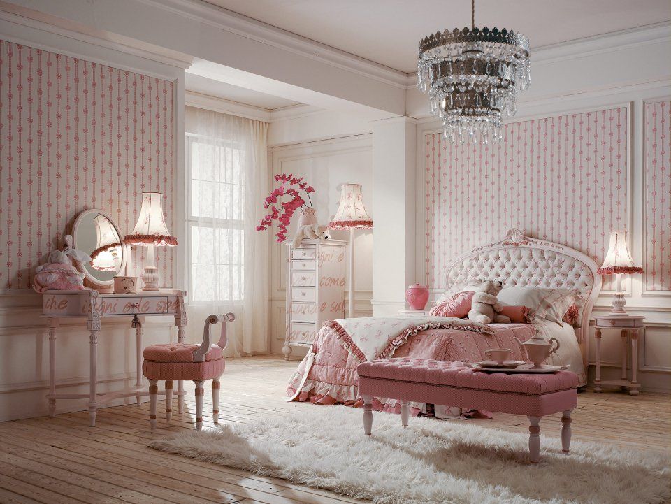 Camera da letto rosa con carta da parati floreale, letto capitonné, toletta, panca e lampadario.