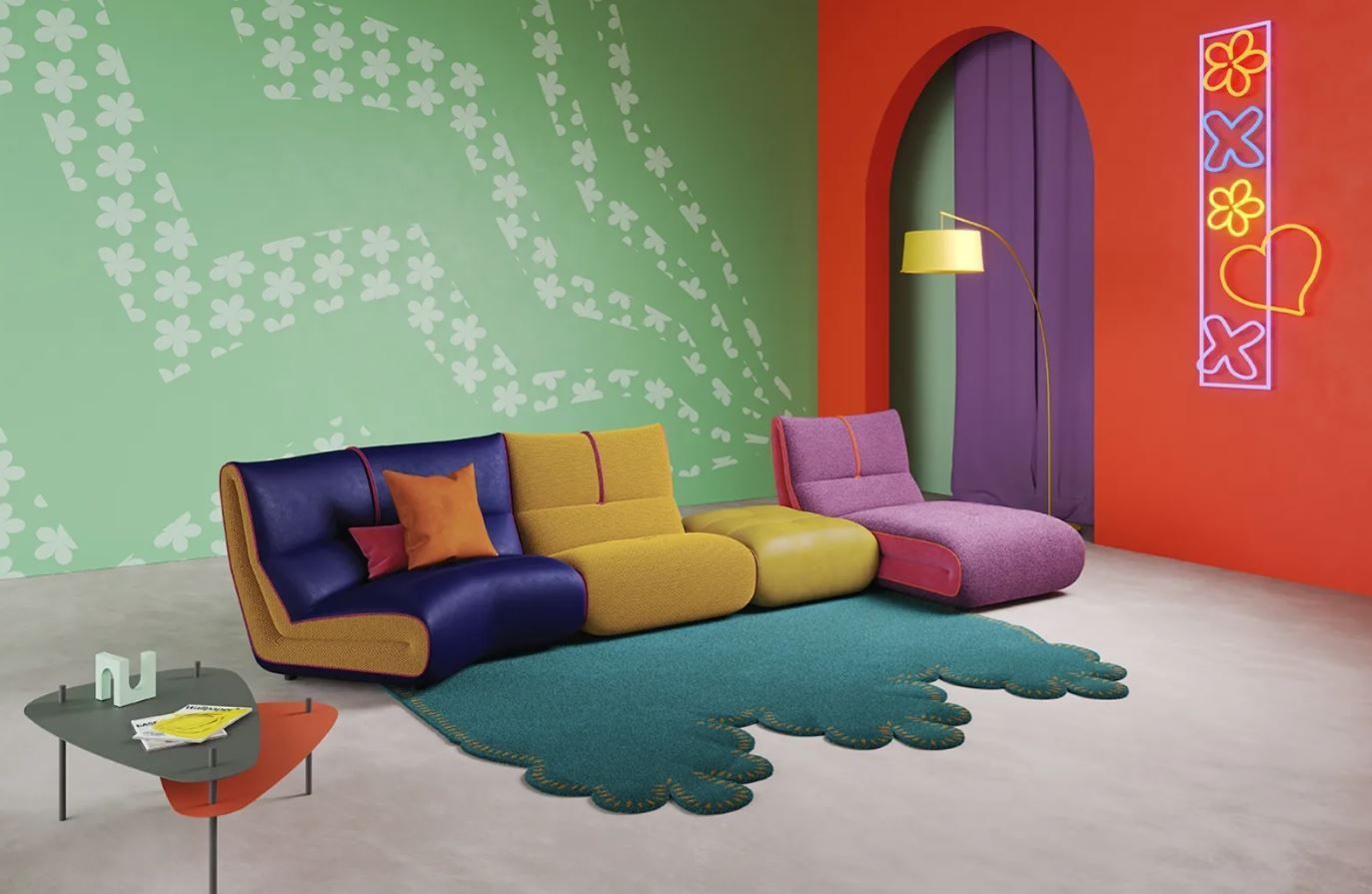 Soggiorno moderno e colorato con divano modulare, tappeto originale e insegna al neon decorativa.