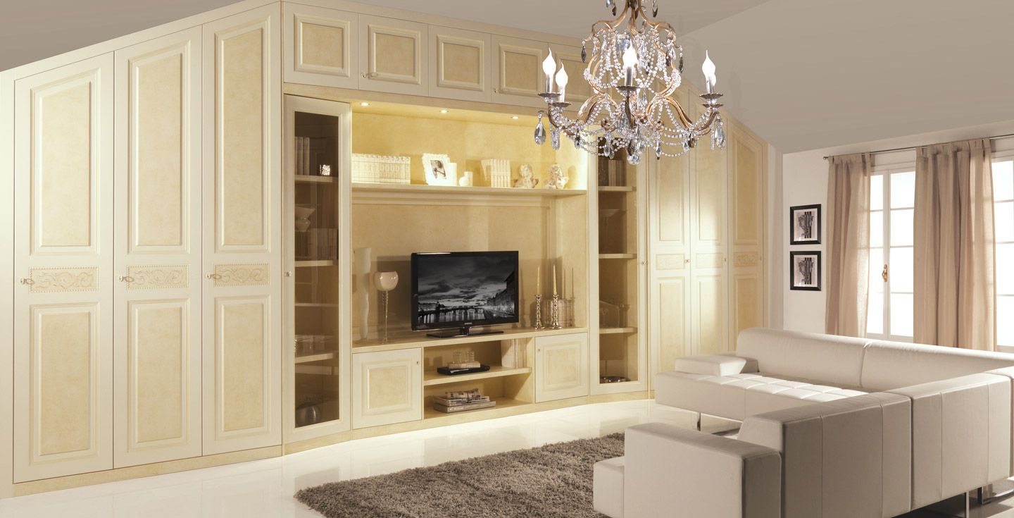 Soggiorno con grandi armadi a muro color crema, TV, divano e lampadario di cristallo.