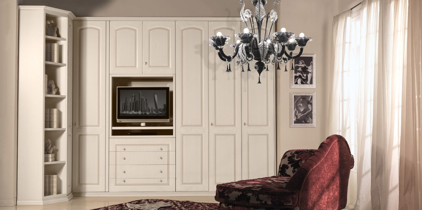 Un soggiorno con mobili a muro e TV a schermo piatto, un lampadario e una chaise longue.