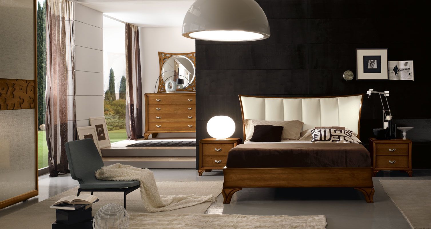 Camera da letto con mobili in legno, tra cui letto, cassettiera, comodini e sedia, con una grande finestra e illuminazione moderna.