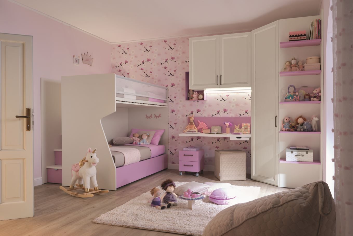 Cameretta per bambini rosa e bianca con letto a castello, scrivania e scaffali pieni di giocattoli.