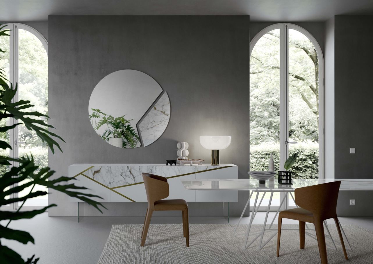 Moderna sala da pranzo con buffet in marmo bianco, specchio rotondo e sedie color cuoio.