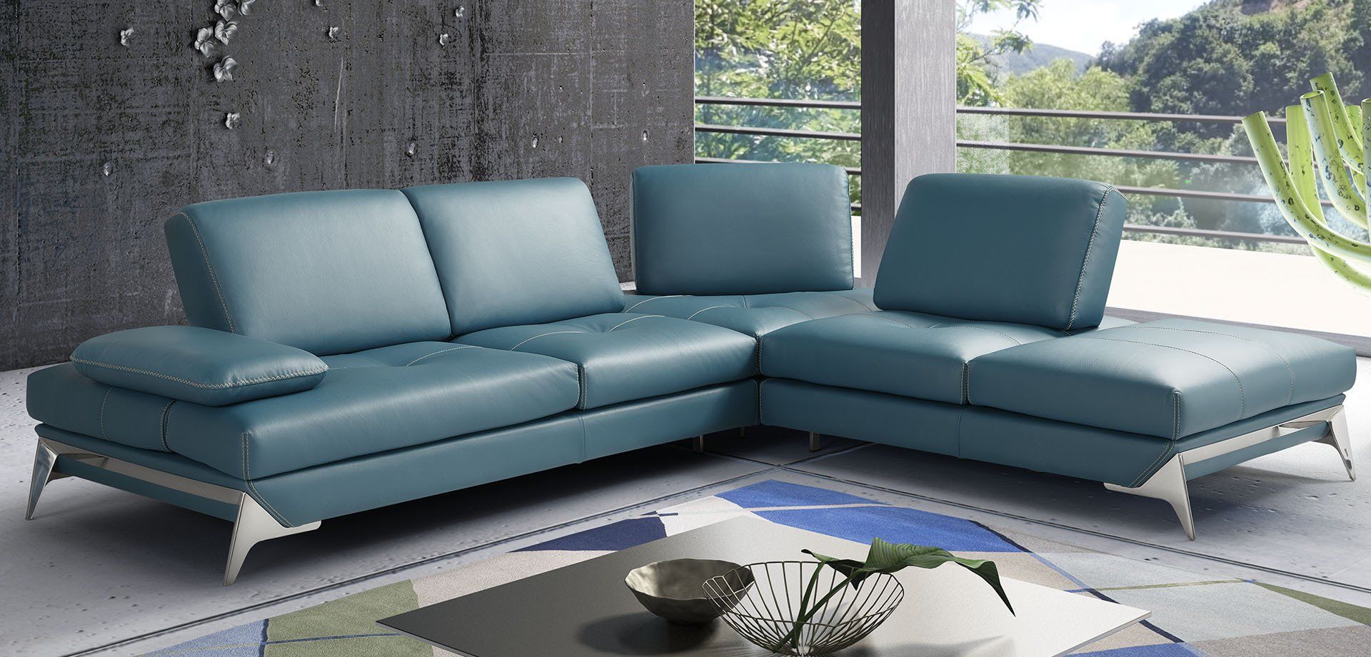 Divano componibile in pelle verde acqua con gambe argentate, in un ambiente moderno per il soggiorno.