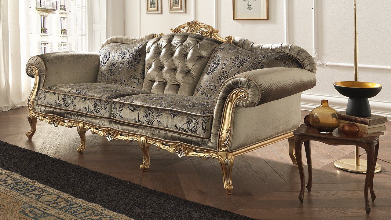 Divano decorato con cornice dorata e tappezzeria a fantasia in un lussuoso soggiorno.