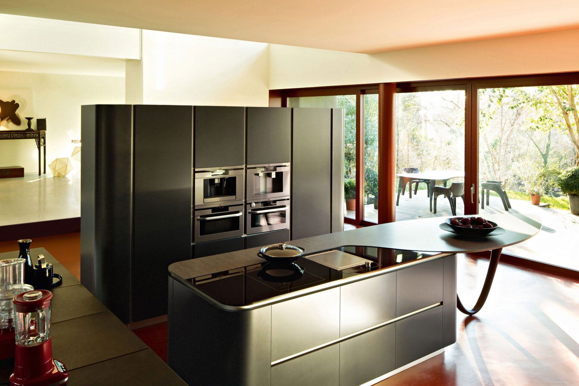 Cucina moderna Snaidero con mobili scuri, isola e ampie finestre che si affacciano sul patio.