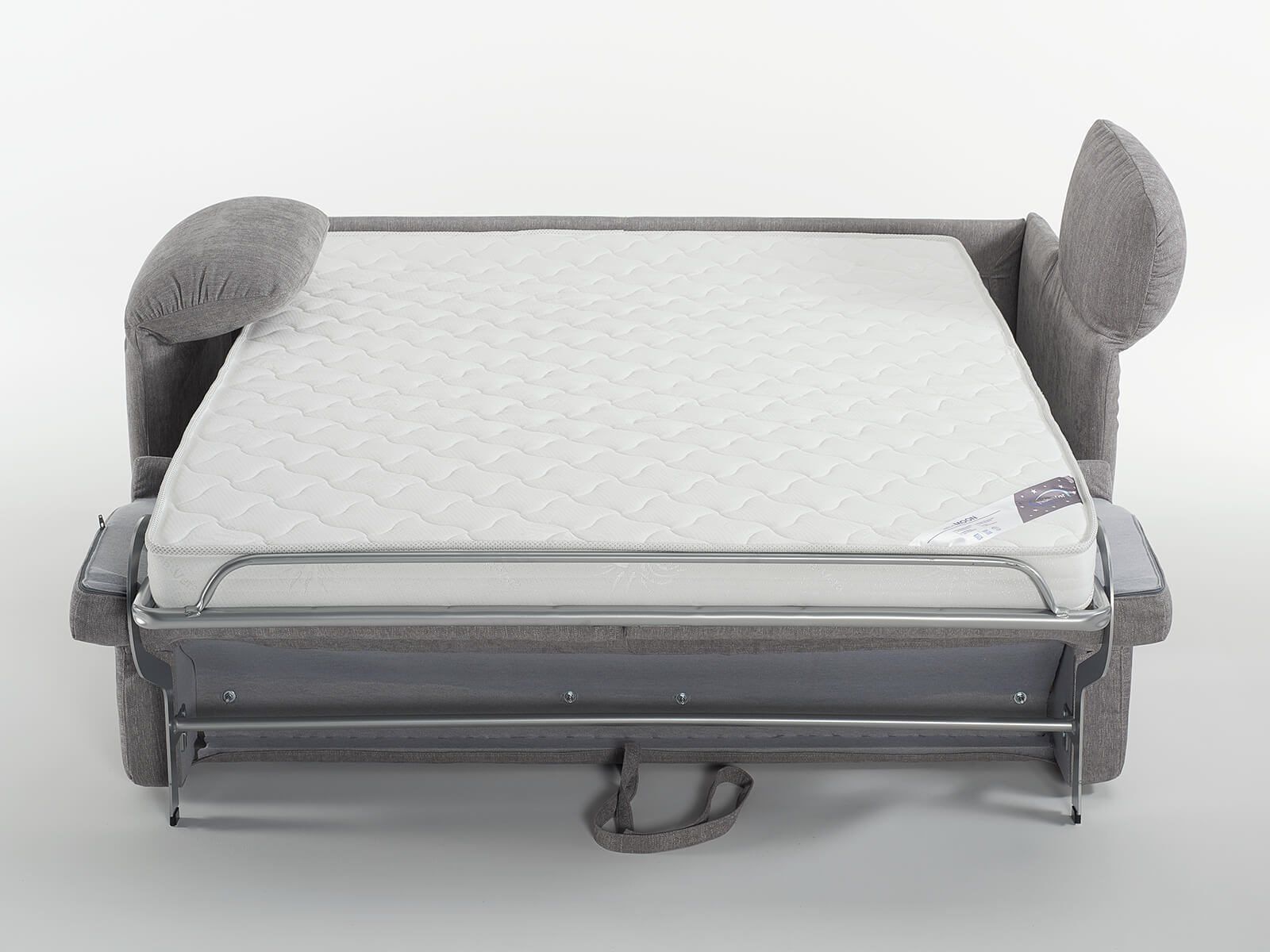Divano letto grigio con materasso bianco aperto e braccioli ripiegati.
