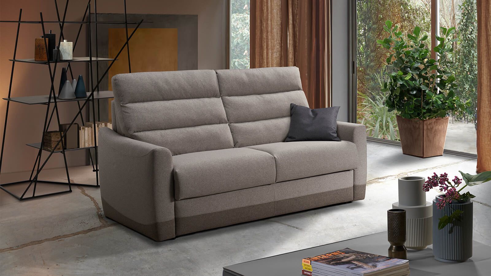 Divano beige in un soggiorno con una pianta e oggetti decorativi.