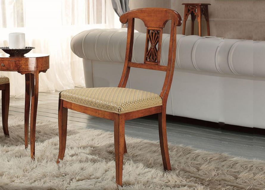 Sedia in legno con seduta intrecciata in un soggiorno con divano bianco e tappeto.
