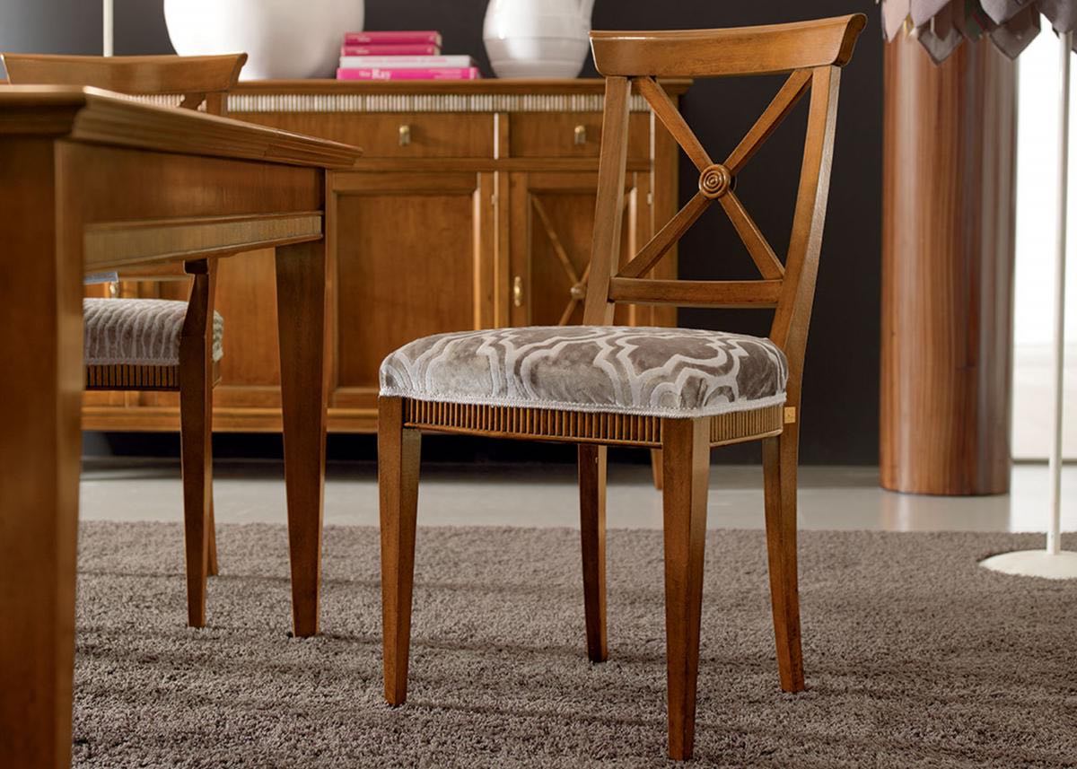 Sedia da pranzo in legno con seduta decorata; tavolo e mobiletto sullo sfondo.