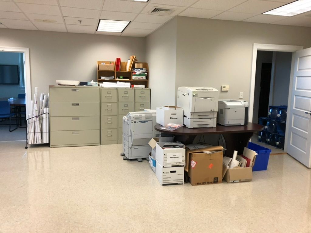 A room with a lot of printers and boxes on the floor